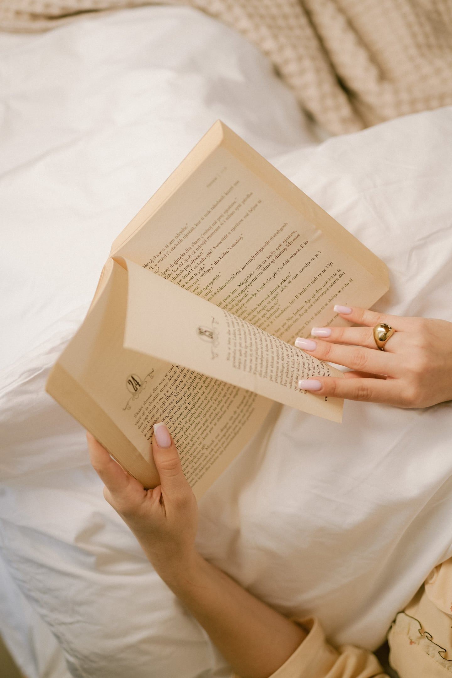 Handen met een open boek op zacht linnen