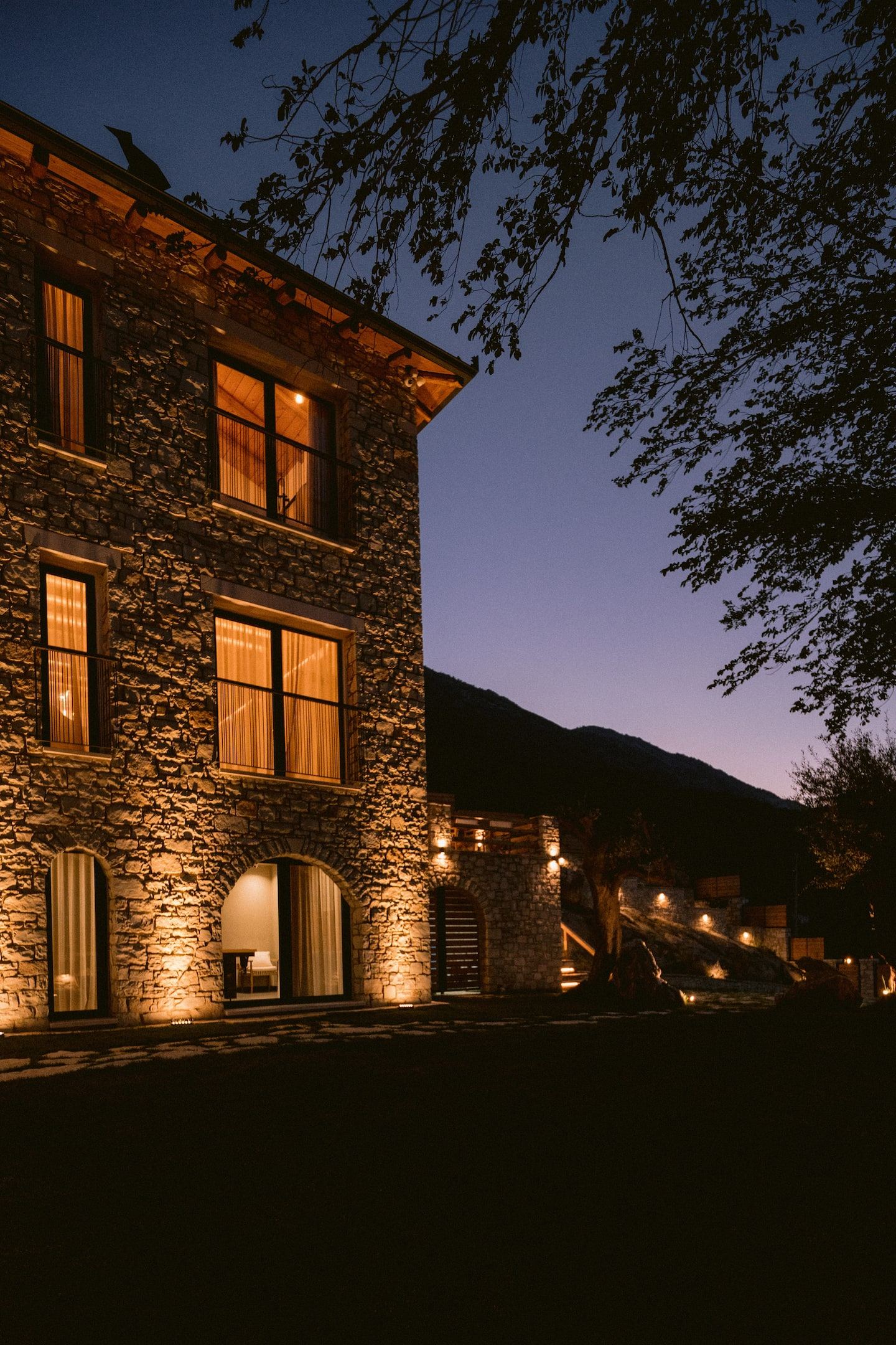 De stenen villa in warm licht tegen de bergen bij het invallen van de avond
